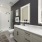 Double sink vanity with LED backlit mirrors and frameless glass shower
